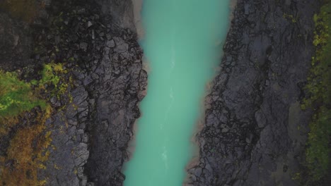 Rising-drone-shot-of-a-deep-blue-Icelandic-river
