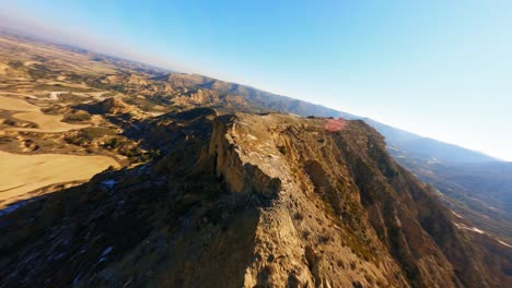FPV-aerial-drone-flying-fast-along-the-ridge-of-a-rock-formation-in-the-Monegros-Desert,-Spain