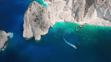 Aerial-View-of-Boat-Leaving-Myzithres-Cape,-Natural-Landmark-and-Scenic-Spot-of-Zakynthos-Island-Greece,-Drone-Shot