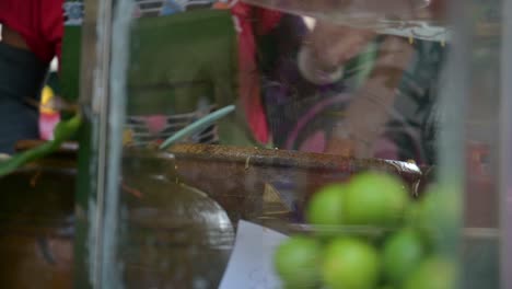 A-local-cook-mixing-and-pounding-a-mixture-of-papaya,-spices,-and-other-vegetables-with-mortar-and-pestle-to-make-Thai-papaya-salad-in-a-roadside-restaurant-in-Bangkok,-Thailand