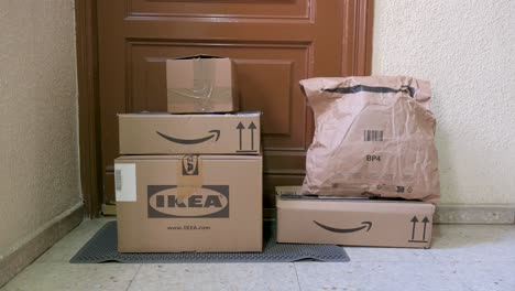 Compras-En-Línea-De-Las-Empresas-Minoristas-Amazon-E-Ikea,-Mientras-Se-Ven-Cajas-De-Cartón-Frente-A-La-Puerta-De-Un-Cliente.