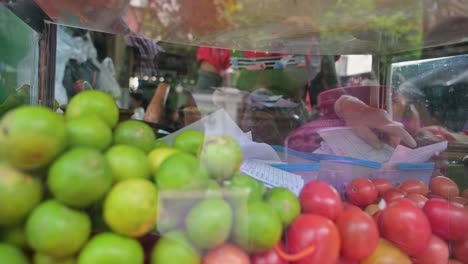 Partly-hidden-local-vendor-sorting-out-the-orders-of-her-customers-for-Somtam-Thai-papaya-salad,-in-a-roadside-restaurant-in-the-streets-of-Bangkok,-Thailand