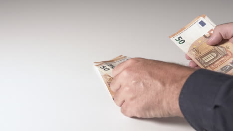 Man-counting-money-on-a-white-desk