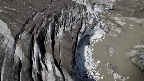 Debris-covered-Pasterze-glacier-melting-ice-cave-due-to-climate-change,-Retreating-glacier-of-Eastern-Alps,-Austria,-Aerial-Closeup