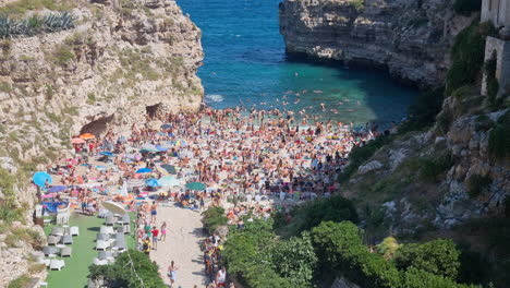 The-crowded-beach-in-Polignano-a-mare-in-Puglia-Italy,-zoom-out