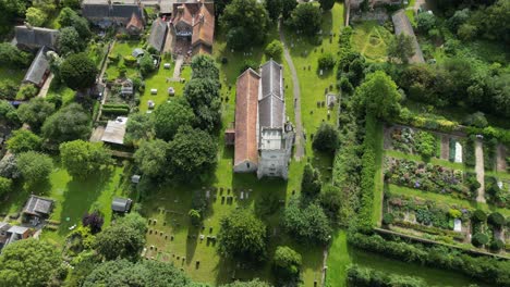 A-top-down-flyover-of-Holy-Cross-church-in-Goodnestone,-Kent,-with-surrounding-greenery-and-cemetery