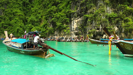 Tracking-shot-of-tour-guides-cruising-long-tailed-boats-on-clear-water-of-Thailand