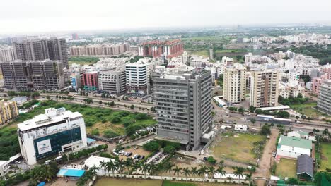 aerial-drone-camera-flying-high-above-and-circling-the-city-with-very-few-buildings-visible-on-either-side-of-the-road,-rainy-season-scene