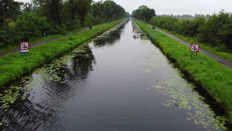 Aerial-view-flying-low-and-over-people-kayakking-through-canal