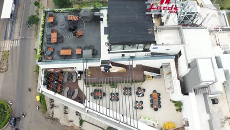 Vista-Aérea-De-Un-Restaurante-Con-Terraza-Construido-En-El-último-Piso-De-Un-Edificio-De-Gran-Altura,-Cámara-Aérea-De-Drones-Filmando-En-Un-ángulo-Holandés-De-Arriba-A-Abajo