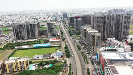 Aerial-cinematic-view-of-city,-ring-road-showing-commercial-buildings-on-all-sides-and-residential-buildings-on-the-back,-new-buildings-under-construction,-airport-in-the-middle-of-the-city