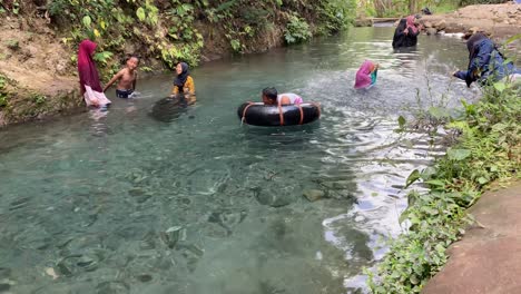 Niños-Nadando-En-Un-Río-Claro-De-Primavera-Usando-Flotadores-De-Ruedas-Profundas-En-Kali-Mudal-Gumuk