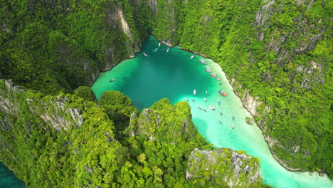 Luftaufnahme-Einer-Wunderschönen-Lagune-Zwischen-Grünen-Bergen-Mit-Türkisfarbenem-Wasser-Und-Parkenden-Booten-Von-Oben-Nach-Unten---Koh-Phi-Phi,-Pi-Leh-Bay