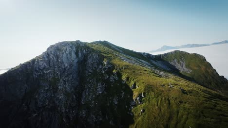 Toma-Cinematográfica-De-Drones-FPV-Estabilizada-Desde-Lofoten-Que-Revela-El-Paisaje-Cubierto-De-Nubes-De-Noruega-Desde-Detrás-De-La-Montaña.