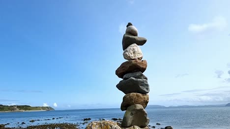 Rising-up-Zen-balanced-stones-towering-over-sunny-peaceful-blue-sky-summer-beach-horizon