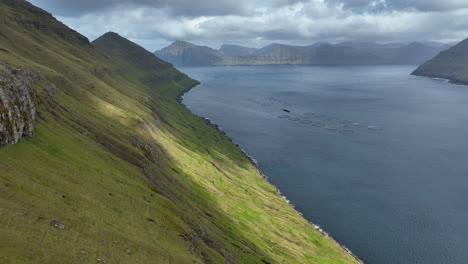 Hvithamar-viewpoint,-Faroe-Islands:-aerial-view-with-lateral-movement-from-the-viewpoint-to-the-high-mountains-and-the-Funningsfjorour-fjord