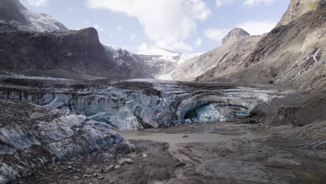 Panoramic-view-of-Pasterze-glacier-melting-ice-cave-due-to-climate-change,-Retreating-glacier-of-Austrian-Alps-covered-in-debris-in-the-lower-part-of-Grossglockner-Mountain,-Aerial-Closeup