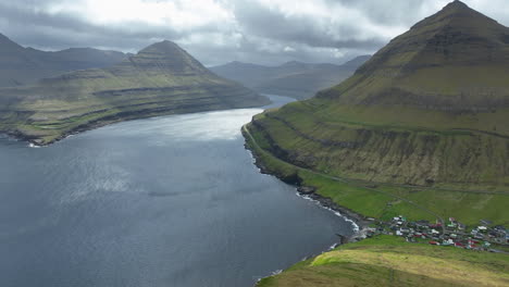 Ithamar-viewpoint,-Faroe-Islands:-aerial-view-traveling-in-to-the-mountains-and-the-Funningsfjorour-fjord