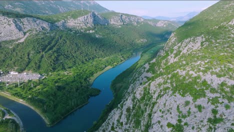 Wide-aerial-pan-of-Cetina-river-and-green-mountains-in-rural-Croatia