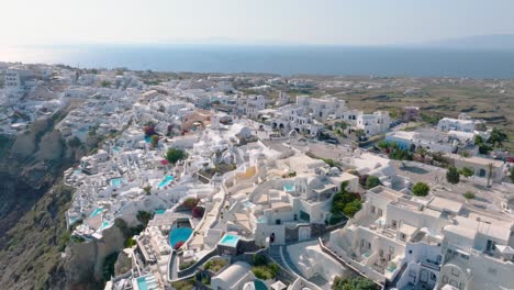 Soar-above-the-captivating-white-architecture-of-Fira,-Santorini,-set-against-the-deep-blue-Aegean-Sea