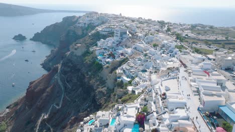 Drift-over-Santorini's-iconic-blue-domed-churches-in-Oia,-bathed-in-the-soft-light-of-the-setting-sun