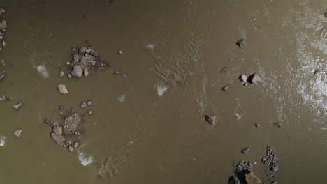 Top-down-aerial-view-of-dead-Pasterze-Glacier-Lake-water-flowing-with-pieces-of-ice-chunks,-Stream-of-muddy-glacier-water