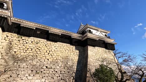 view-over-steep-exterior-walls-of-Matsuyama-castle-against-a-blue-sky