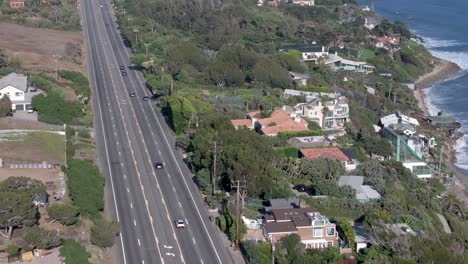 Aerial-view-following-Pacific-coast-highway-traffic-travelling-down-Malibu-coastline