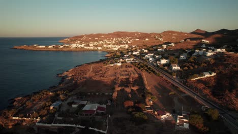 Drone-trucking-pan-along-coastal-villas-and-homes-at-golden-hour-sunset,-long-shadows-in-syros-greece