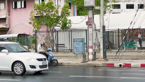 Motorcycle-Driver-Stopped-on-the-Side-of-the-Road-Texting-on-his-Mobile-Phone,-Bangkok,-Thailand