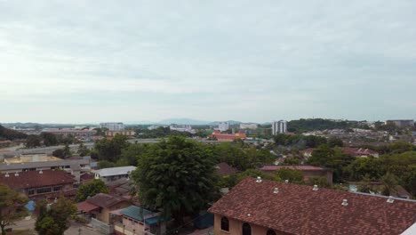 Slow-pan-from-right-to-left-captures-a-high-angle-city-panorama-of-Melaka,-Malaysia,-during-a-late-afternoon-with-a-lightly-clouded-sky