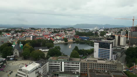 Aerial-dolly-toward-Breiavatnet-lake-with-fountain-in-Stavanger-city,-Norway