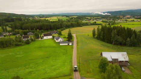 Farm-Tractor-Driving-Across-Dirt-Road-On-The-Farm-Village-In-South-Eastern-Norway