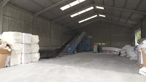 Dolly-forward-into-paper-recycling-center-facility-with-conveyor-belt,-other-equipment