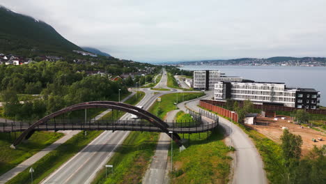 Bus-passing-under-a-bridge-in-Tromso-coastal-city,-Norway