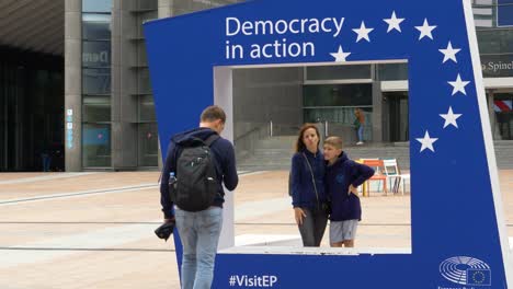 Father-Taking-Photo-Of-Wife-And-Daughter-Beside-Large-EU-Photo-Frame-Attraction-Outside-European-Parliament-Building-In-Brussels