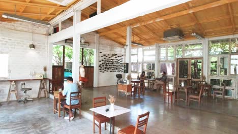 Interior-Panning-Shot-of-a-Thai-Cafe-in-Bangkok-with-People-Seated-Drinking-Coffee,-Thailand