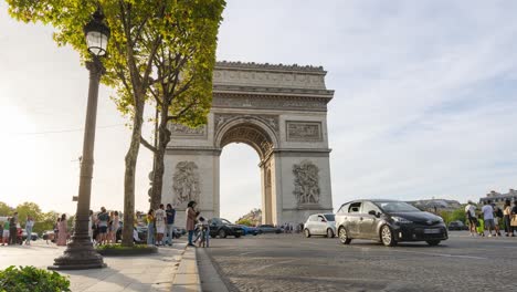 Time-Lapse-of-Arc-de-Triomphe-in-Paris:-Tourists-Taking-Photos,-Cars-Zooming-By,-Glorious-Sunset-Sky,-Dynamic-Urban-Activity-Captured