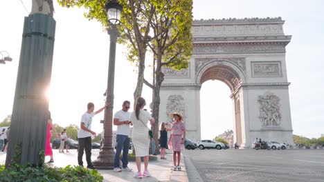 Turistas-Posando-Para-Fotos-En-El-Arco-Del-Triunfo-En-París-Durante-La-Puesta-De-Sol:-Momentos-Capturados,-Atmósfera-De-La-Hora-Dorada,-Emblemático-Monumento-Francés,-Luz-Nocturna