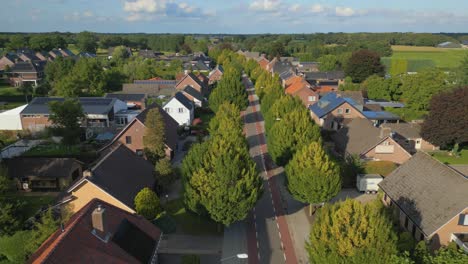 Lowering-crane-shot-of-typical-Dutch-street-lane-with-trees-in-village