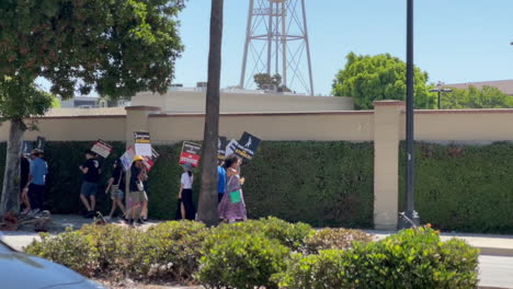 WGA-and-SAG-AFTRA-Strikers-Picketing-Outside-of-Warner-Brothers-Studio-Gate-4,-Pan-up-to-Warner-Brothers-Water-Tower-on-W-Olive-Ave