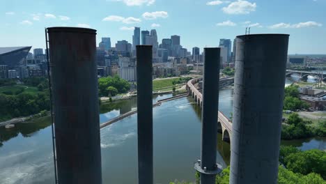 Old-smokestacks-in-front-of-Minneapolis,-Minnesota-waterfront-and-skyline