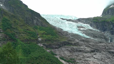 Tilt-up-from-tourists-in-Fjaerland-to-Boyabreen-Jostedal-glacier-mountain-view