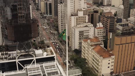 Aerial-establishing-shot-of-Brazilian-flag-and-traffic-on-highway-in-downtown-of-Sao-Paulo-City