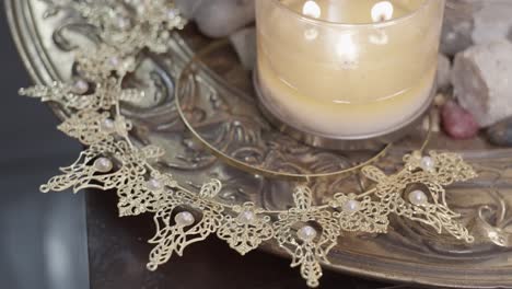 Zoom-on-a-silver-plate-with-a-lit-candle-on-a-glass