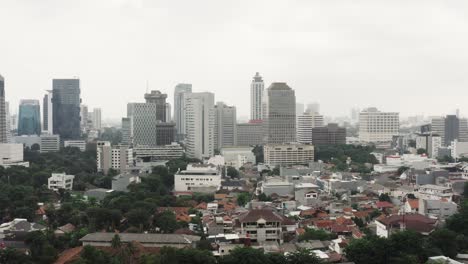 Toma-Aérea-Descendente-Del-Horizonte-Con-Edificios-Rascacielos-En-La-Ciudad-De-Yakarta-En-Un-Día-Nublado