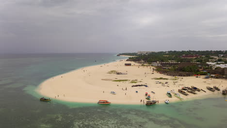 Drone-view-of-beautiful-sandy-beach-and-turquoise-ocean-with-boats,people-and-clouds-sky,-Zanzibar,-Kendwa,-Africa,-shot-at-24-fps