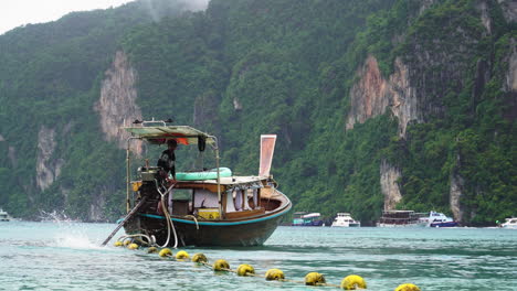 Barquero-Propulsando-Y-Dirigiendo-Un-Barco-De-Cola-Larga-En-El-Mar-De-Andamán-En-Las-Islas-Ko-Phi-Phi,-Tailandia