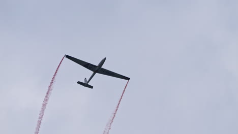 Planeador-Realizando-Maniobras-Desafiantes-Y-Dejando-Rastros-De-Humo-Rojo-En-El-Espectáculo-Aéreo