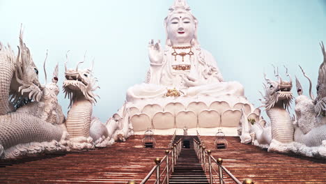 Walking-up-stairway-with-dragon-sculptures-to-huge-Guanyin-statue,-POV